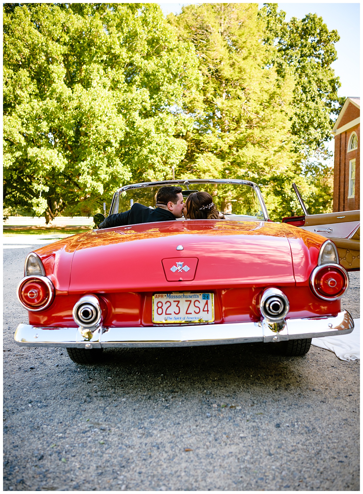 bride and groom kissing in vintage red Thunderbird
