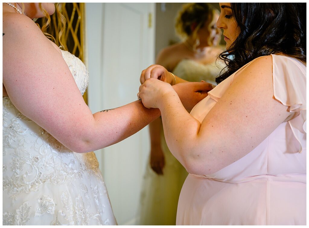 maid of honor putting on bride's bracelet