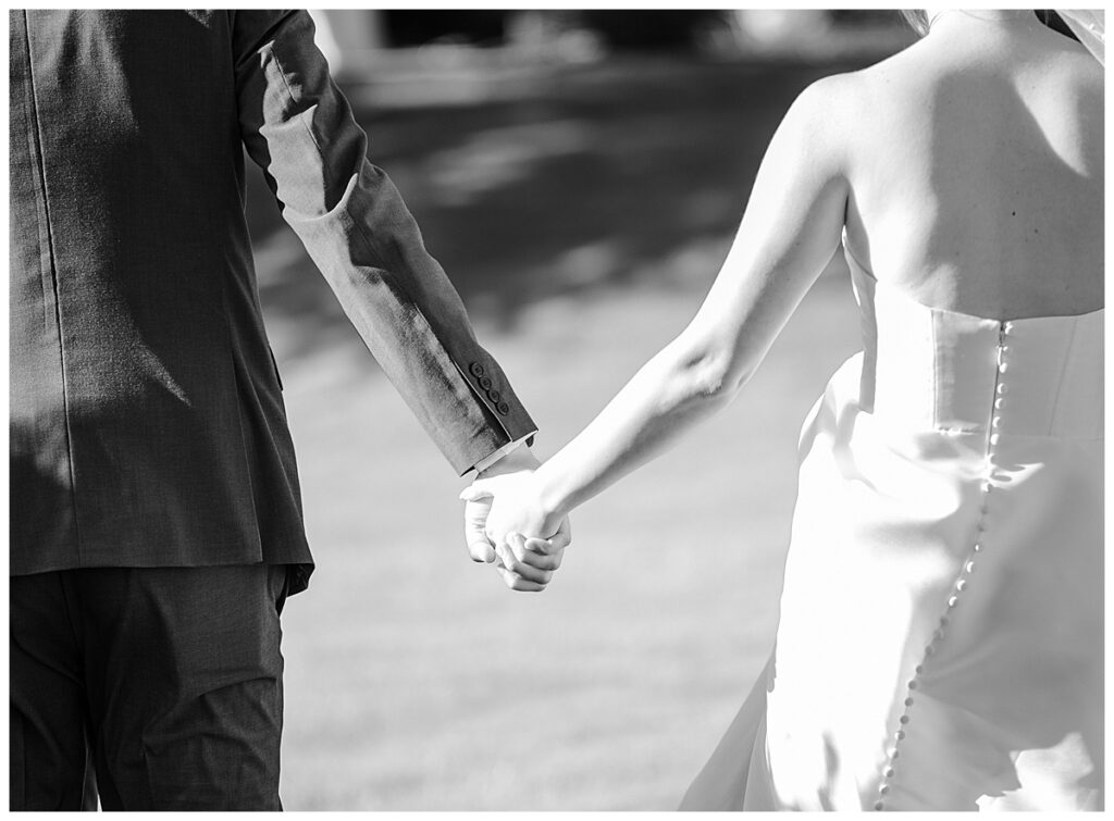 bride and groom holding hands in black and white