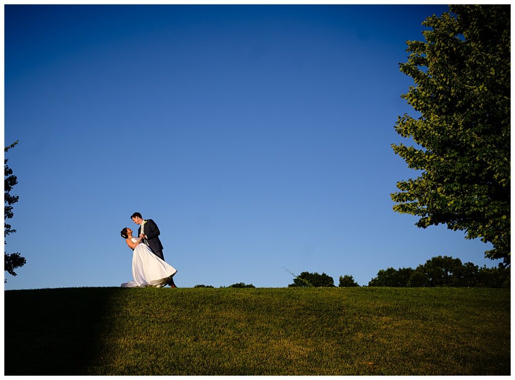 bride and groom in a dip on top of a hill