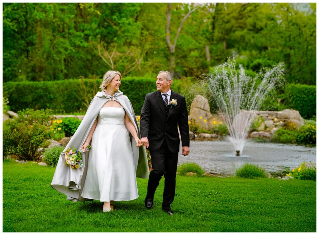 bride and groom walking hand in hand in Sagamore Inn's gardens
