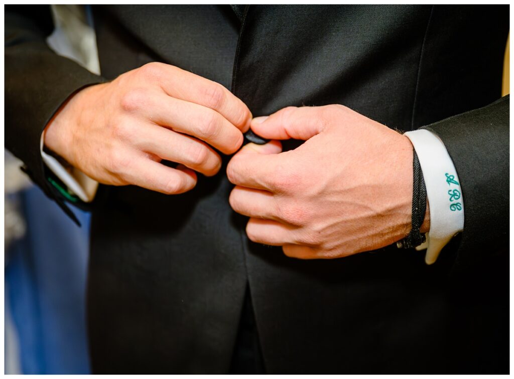 groom buttoning up jacket with embroidered cuff